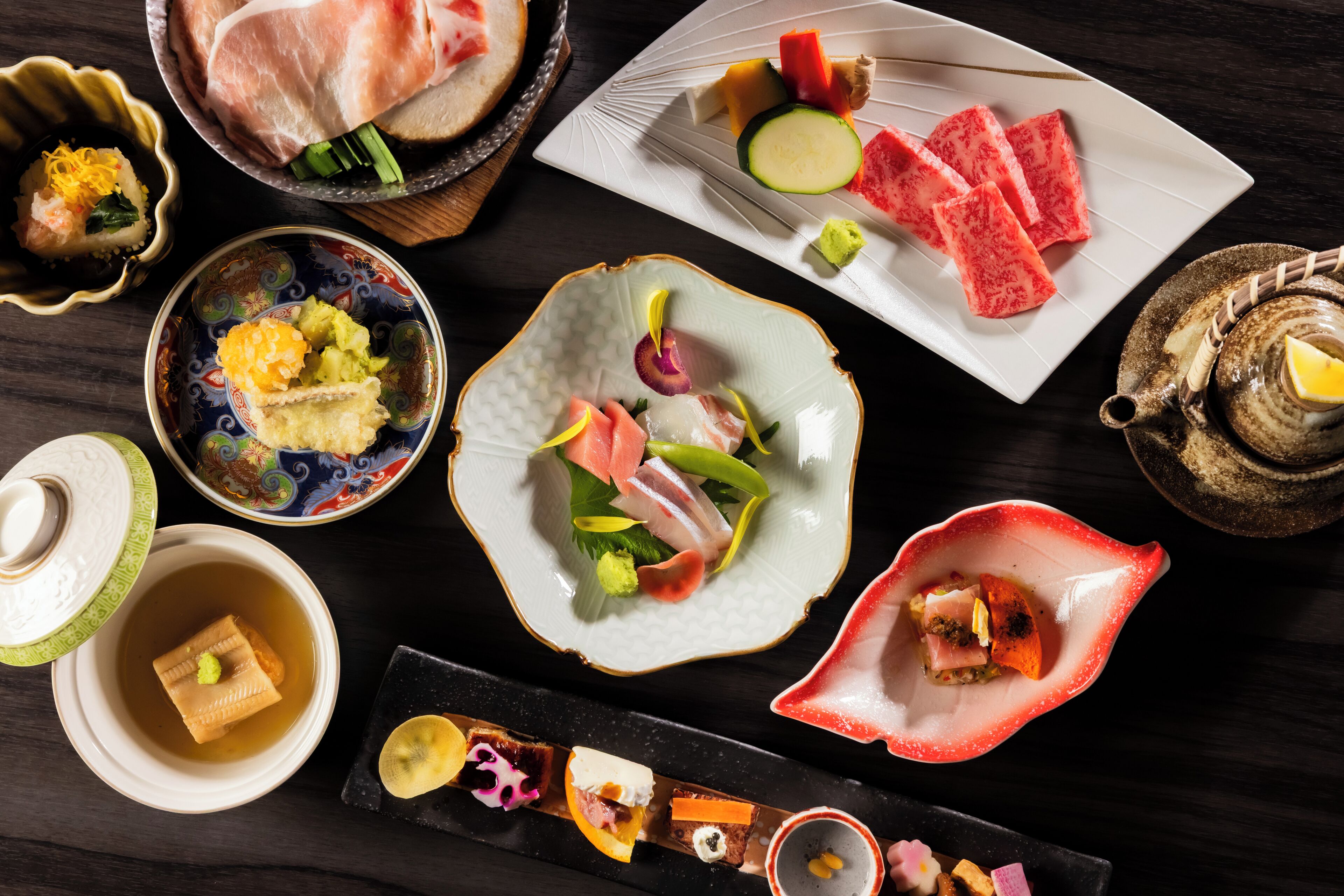 Een selectie gerechten op een tafel, waaronder sushi, sashimi en andere hapjes.