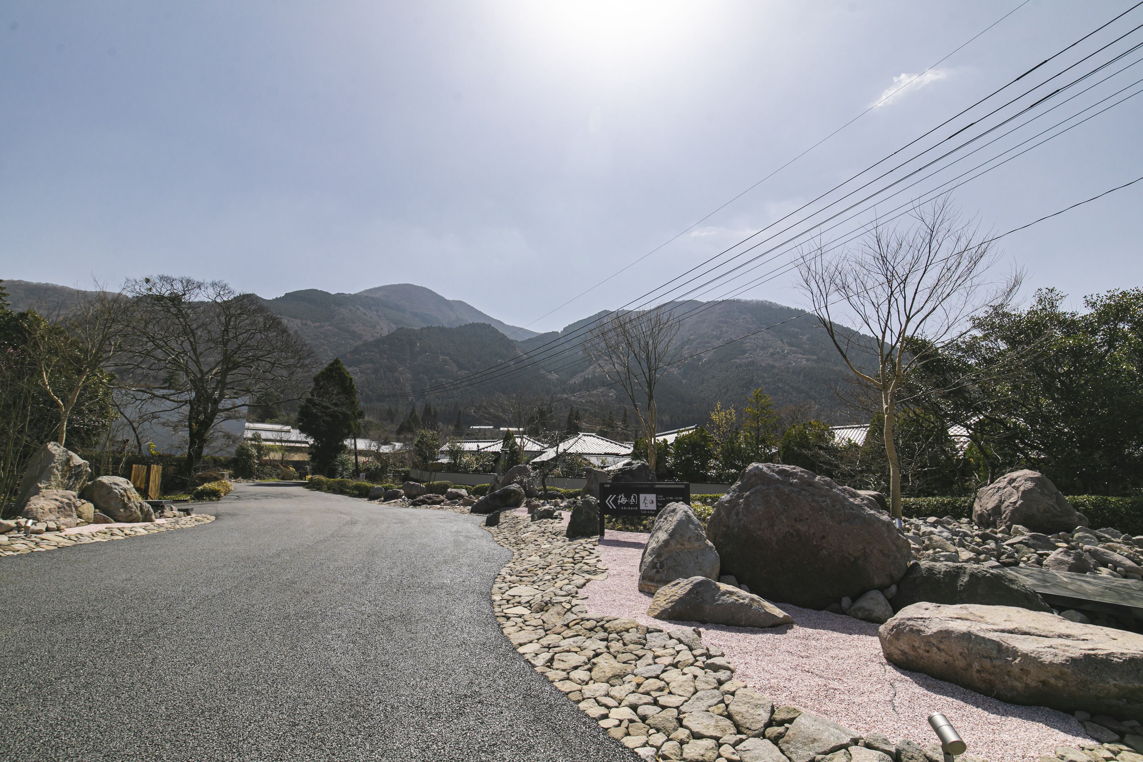 A paved road curving through a mountainous area with large rocks and a sign indicating a direction.