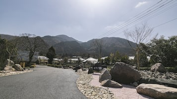 A paved road curving through a mountainous area with large rocks and a sign indicating a direction.