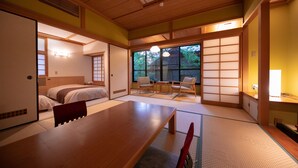 A traditional Japanese-style room with tatami flooring, a low wooden table, and a futon bed. - Yufuin Baien Garden Resort (Yufu)