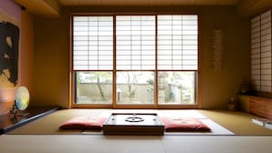 A traditional Japanese room with tatami flooring, a shoji screen window, and a tatami mat bed. - Futabaso (Hikone)