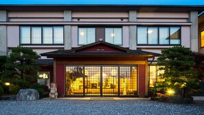 A hotel entrance with a covered walkway, large windows, and a traditional Japanese garden. - Futabaso (Hikone)