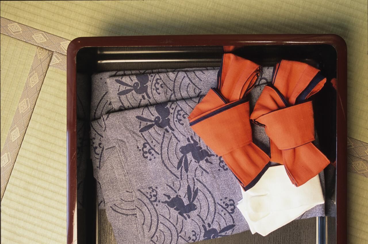 A suitcase with a floral pattern and a folded orange garment inside.