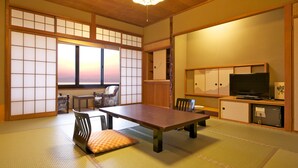 A traditional Japanese room with tatami flooring, a low table, chairs, a television, and sliding doors. - Futabaso (Hikone)