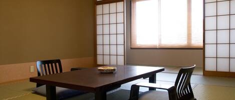 A traditional Japanese room with tatami flooring, a low table, and two chairs.