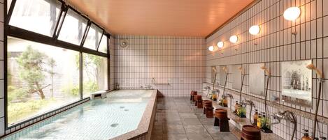 Una amplia piscina interior con suelo de baldosas y bancos a lo largo del borde.