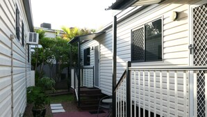 Una propiedad residencial con un patio cubierto, un pequeño espacio de estar al aire libre y una escalera que conduce a la entrada.