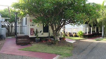 A mobile home with a small garden area, a fire extinguisher mounted on the wall, and a paved walkway.