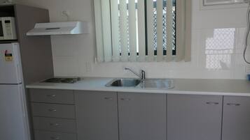 A kitchen with a built-in stove, a sink, and grey cabinets.