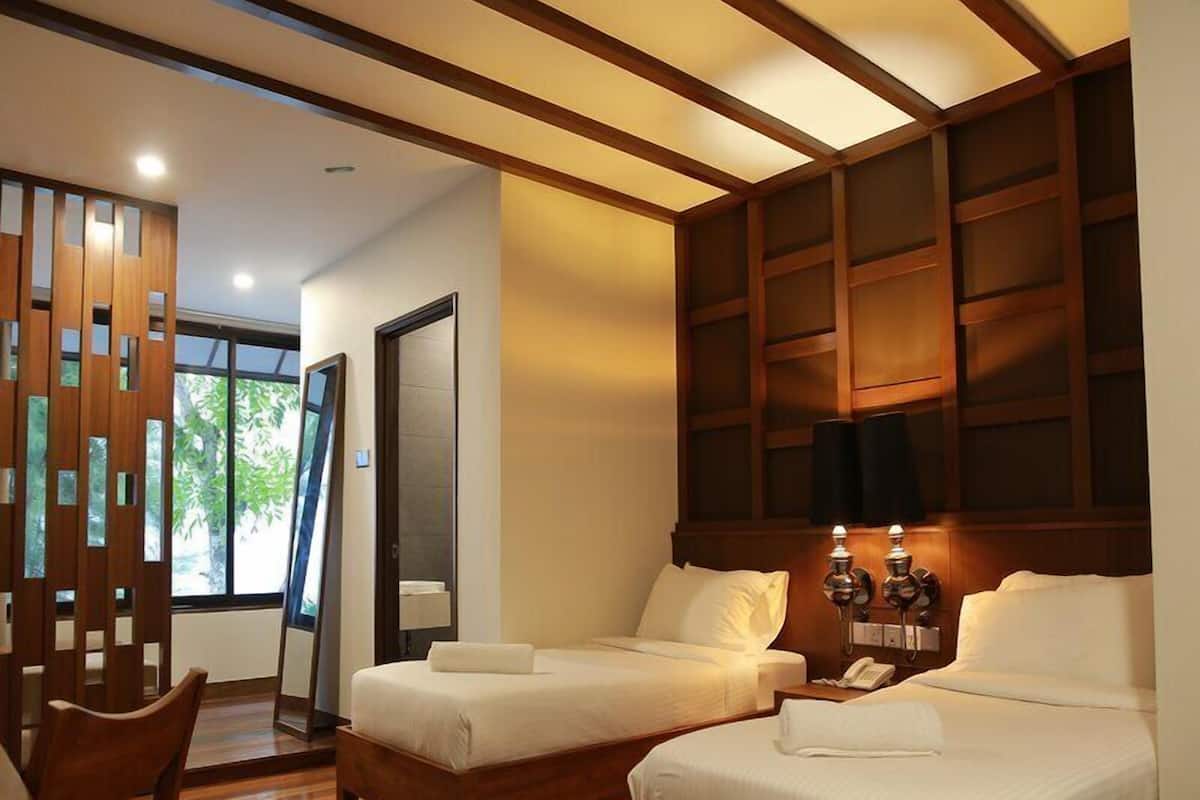 Ein Hotelzimmer mit zwei Betten, einer Holzbalkendecke, einem großen Fenster und einer Holzwand mit Ausschnitten.