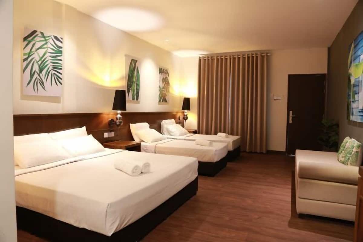 Ein Hotelzimmer mit drei Betten, einer Schlafcouch und Wandbildern.