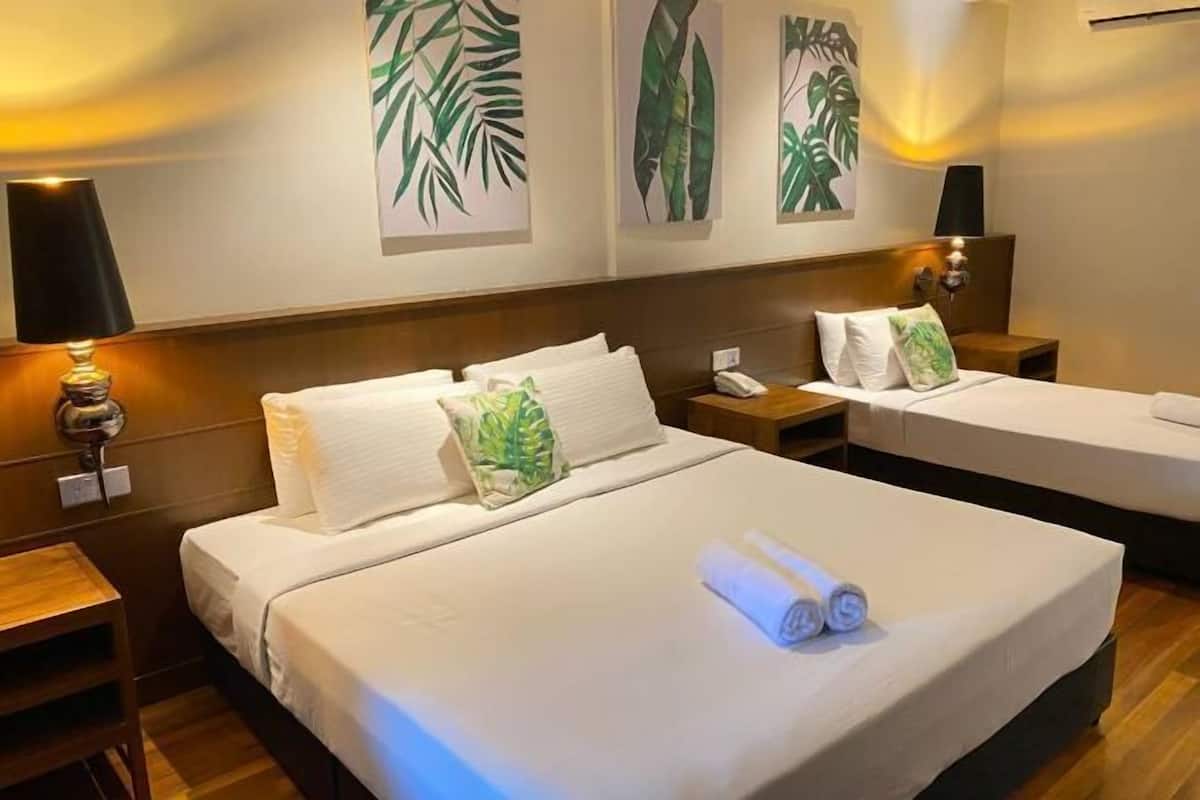 Ein Hotelzimmer mit zwei Betten, einem Nachttisch, einer Lampe und Wandbildern.