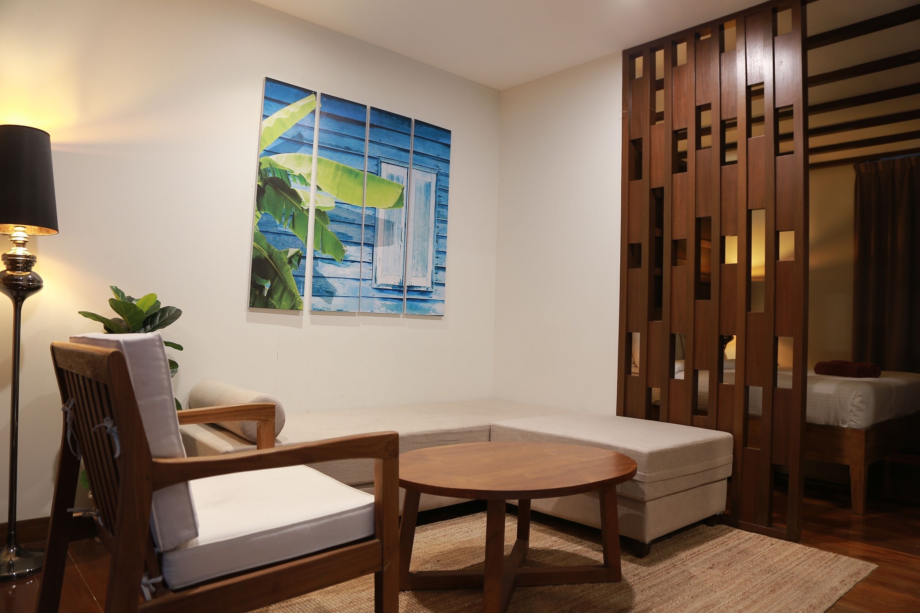 A modern living room with a sofa, a round wooden table, a floor lamp, and a decorative wooden partition.