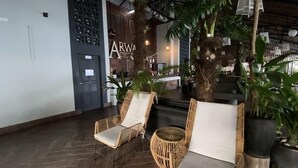 Un vestíbulo con sillones de mimbre y una planta grande en maceta.