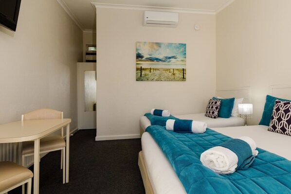 Una habitación de hotel con una cama, un escritorio y un cuadro en la pared.