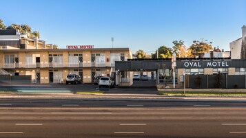 Um motel com uma placa indicando "OVAL MOTEL" e um estacionamento com vários carros.