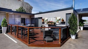 Terraza en la azotea con mobiliario exterior, plantas en macetas y una chimenea.
