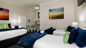 A hotel room with two beds, a desk, and chairs.