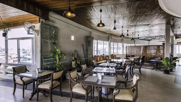 A spacious restaurant with high ceilings and natural light, featuring wooden furniture and potted plants. - Paradise Hotel (Phnom Penh)
