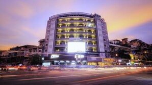 A multi-story hotel with a prominent sign on the facade, multiple balconies, and a well-lit entrance. - Paradise Hotel (Phnom Penh)