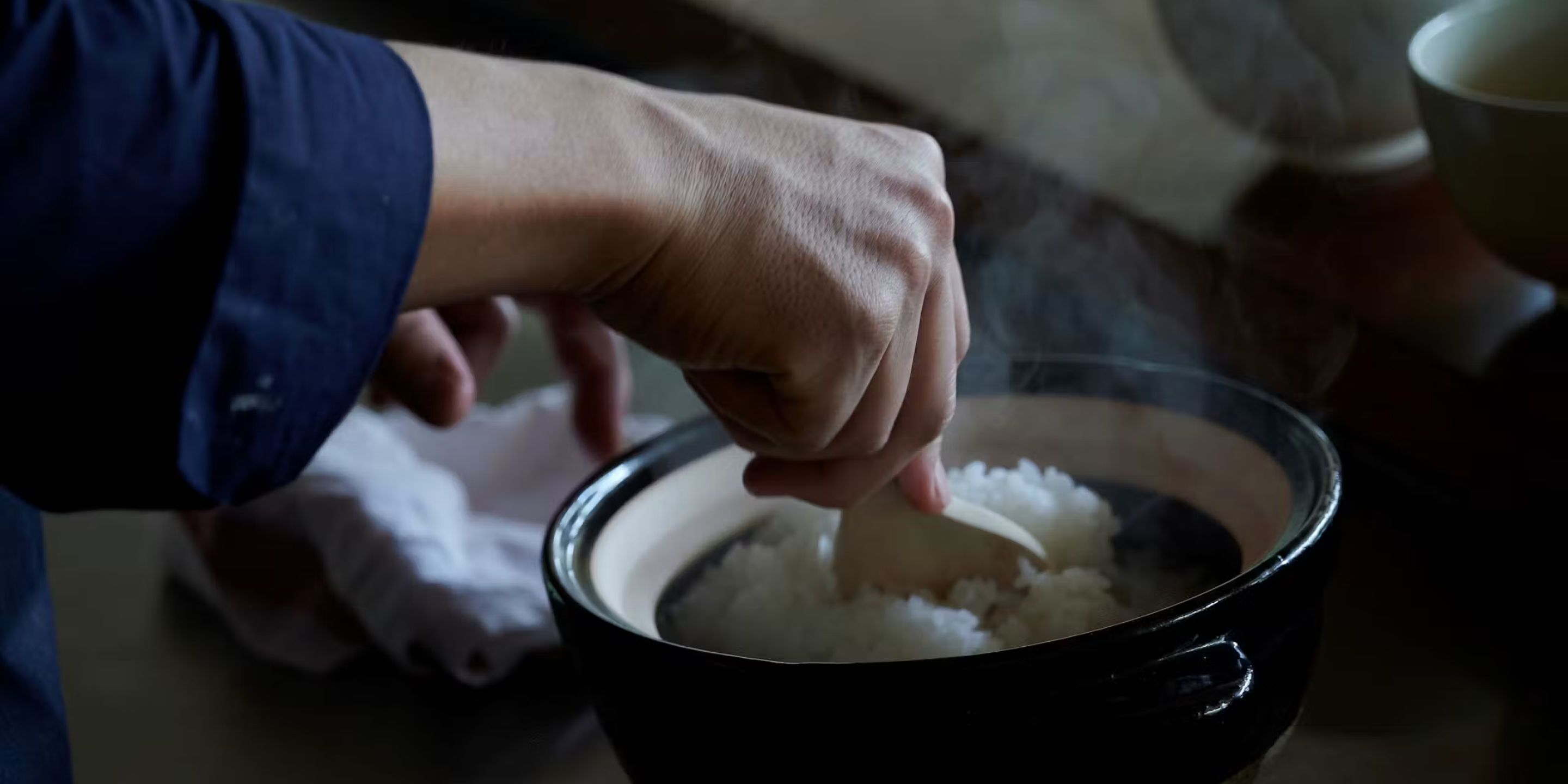 Una mano removiendo arroz en un tazón.