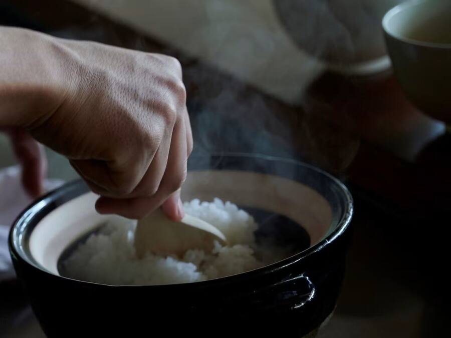 Una mano removiendo arroz en un tazón.