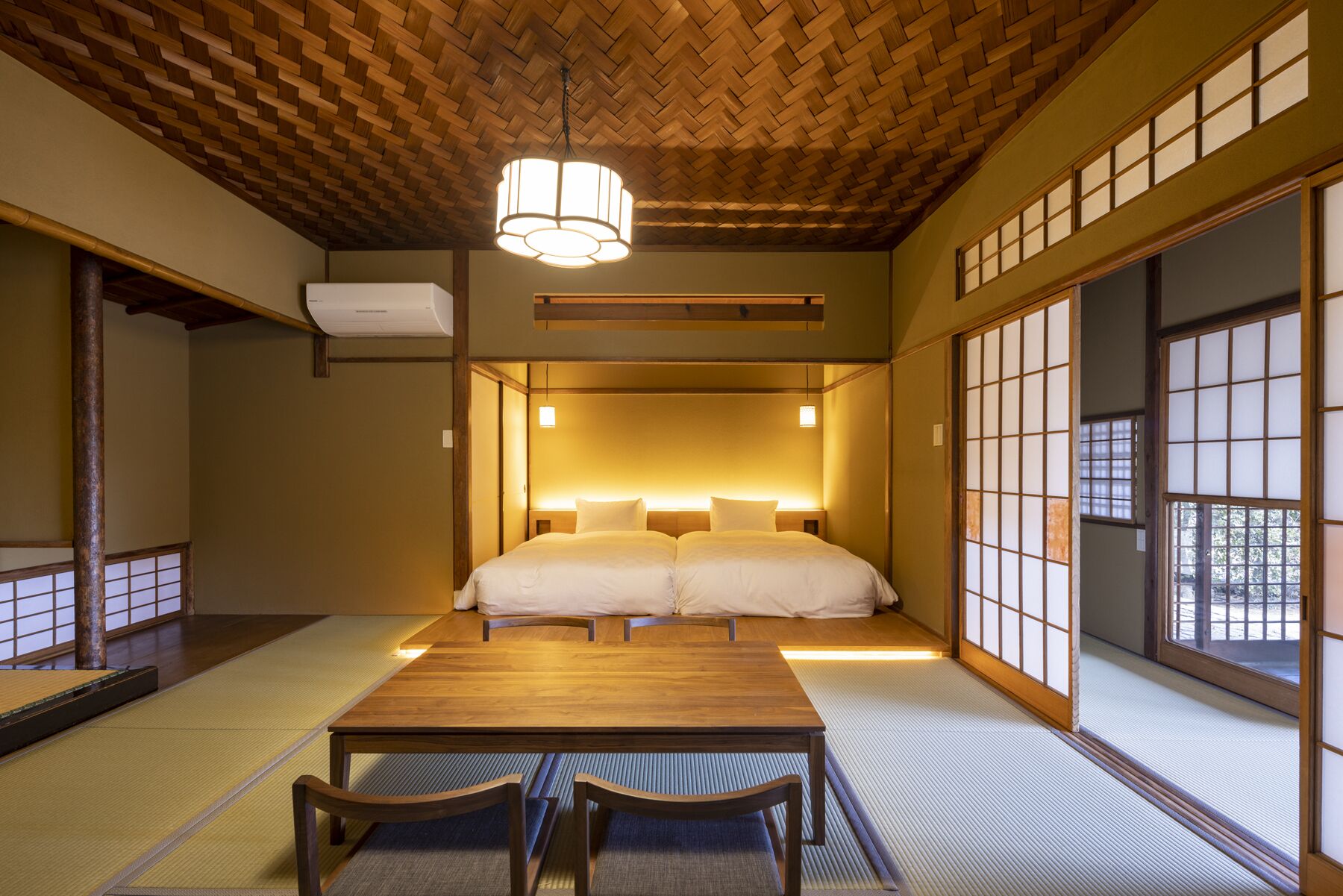 Una habitación tradicional japonesa con suelo de tatami, techo de madera bajo y puertas correderas shoji.
