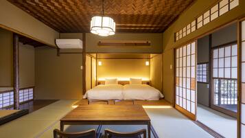 Una habitación tradicional japonesa con suelo de tatami, techo de madera bajo y puertas correderas shoji.