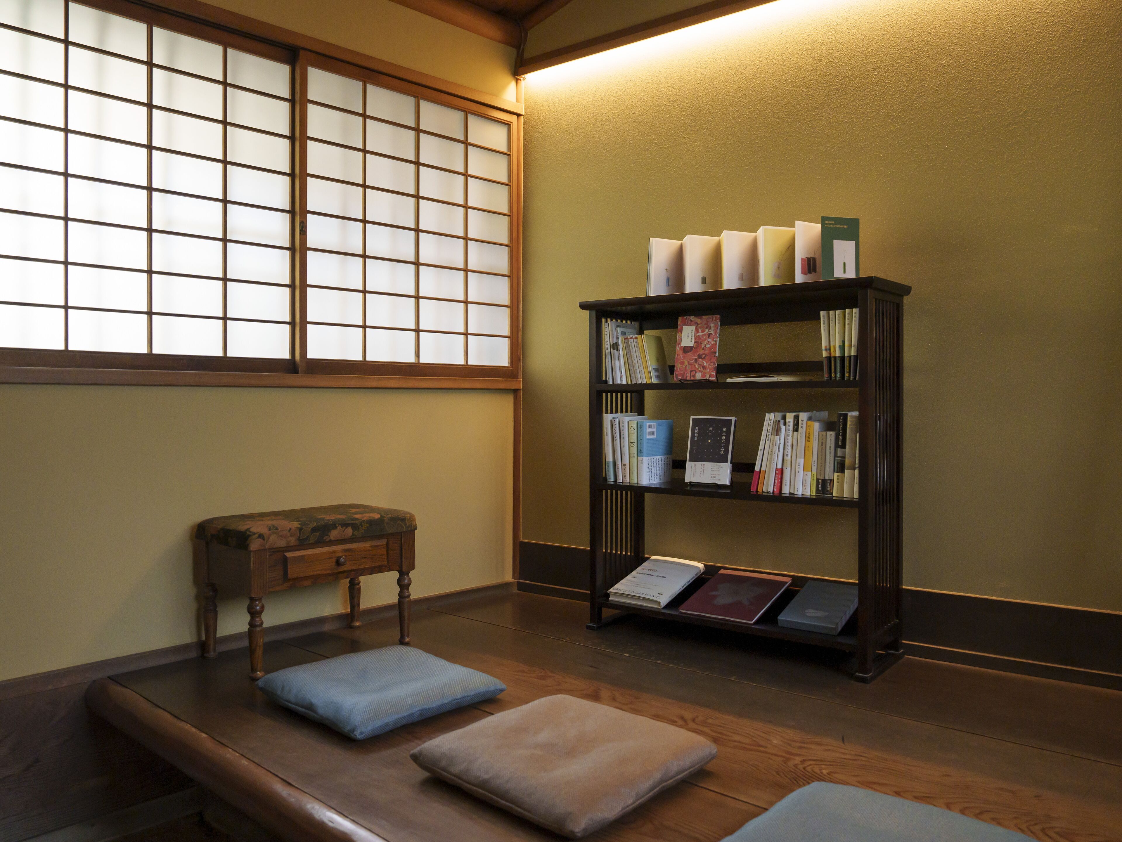A room with a tatami mat seating area, a traditional Japanese sliding door, and a bookshelf with books and decorative items.