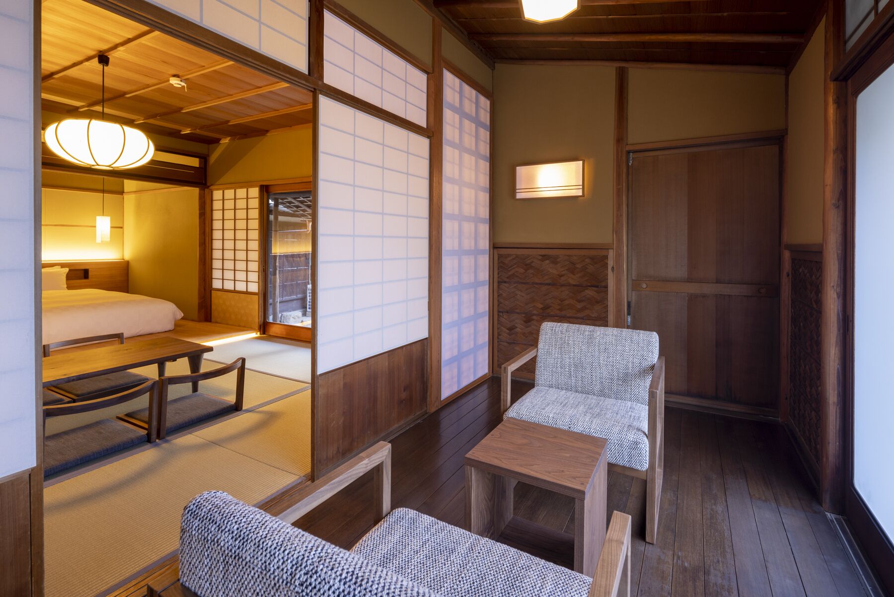 Ein traditioneller japanischer Raum mit Tatami-Böden, einem niedrigen Holzbett, einem Tisch und Stühlen.