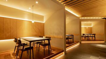 Um interior moderno com paredes de madeira, uma mesa de jantar central e teto inclinado com iluminação embutida.