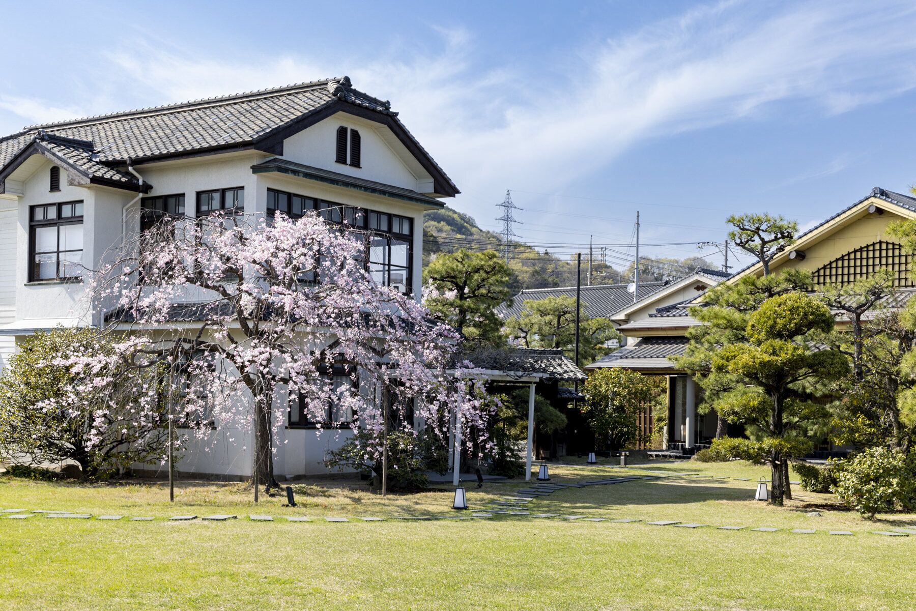 Et traditionelt japansk hus med have, blandt andet med kirsebærtræer og en velplejet græsplæne.