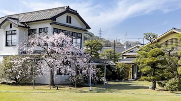 Et traditionelt japansk hus med have, blandt andet med kirsebærtræer og en velplejet græsplæne.