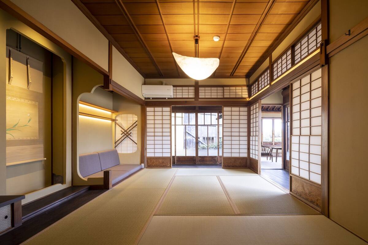 Un interior japonés tradicional con suelo de tatami, puertas correderas y una lámpara colgante.