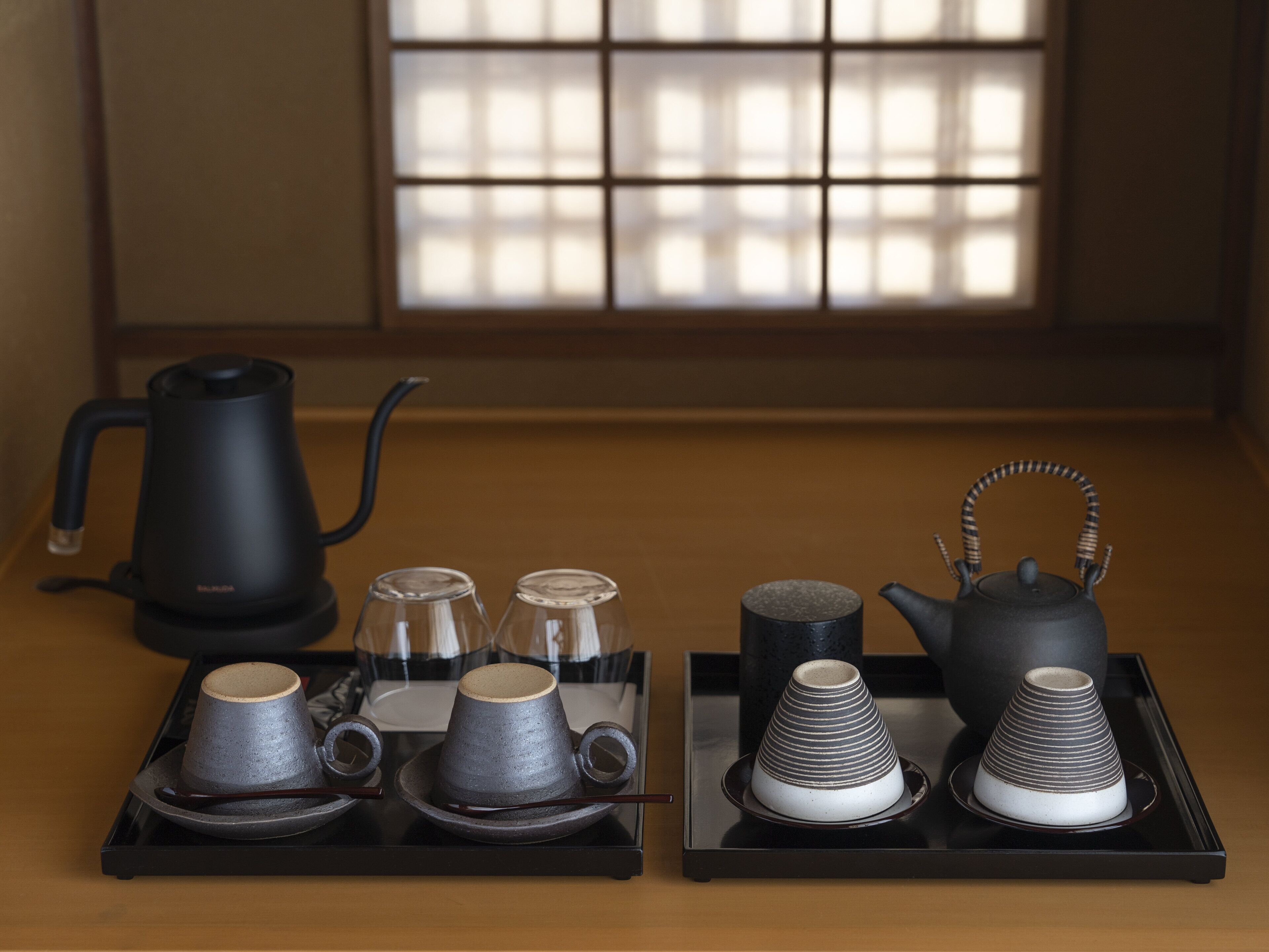 A tea set with a kettle, cups, and a teapot on a tray.