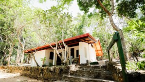 A rustic building with a red roof, surrounded by lush greenery and stone steps leading up to it. - The Waves Beach Chalets (Tangalle)