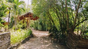 A pathway leading through a lush garden with a wooden structure. - The Waves Beach Chalets (Tangalle)