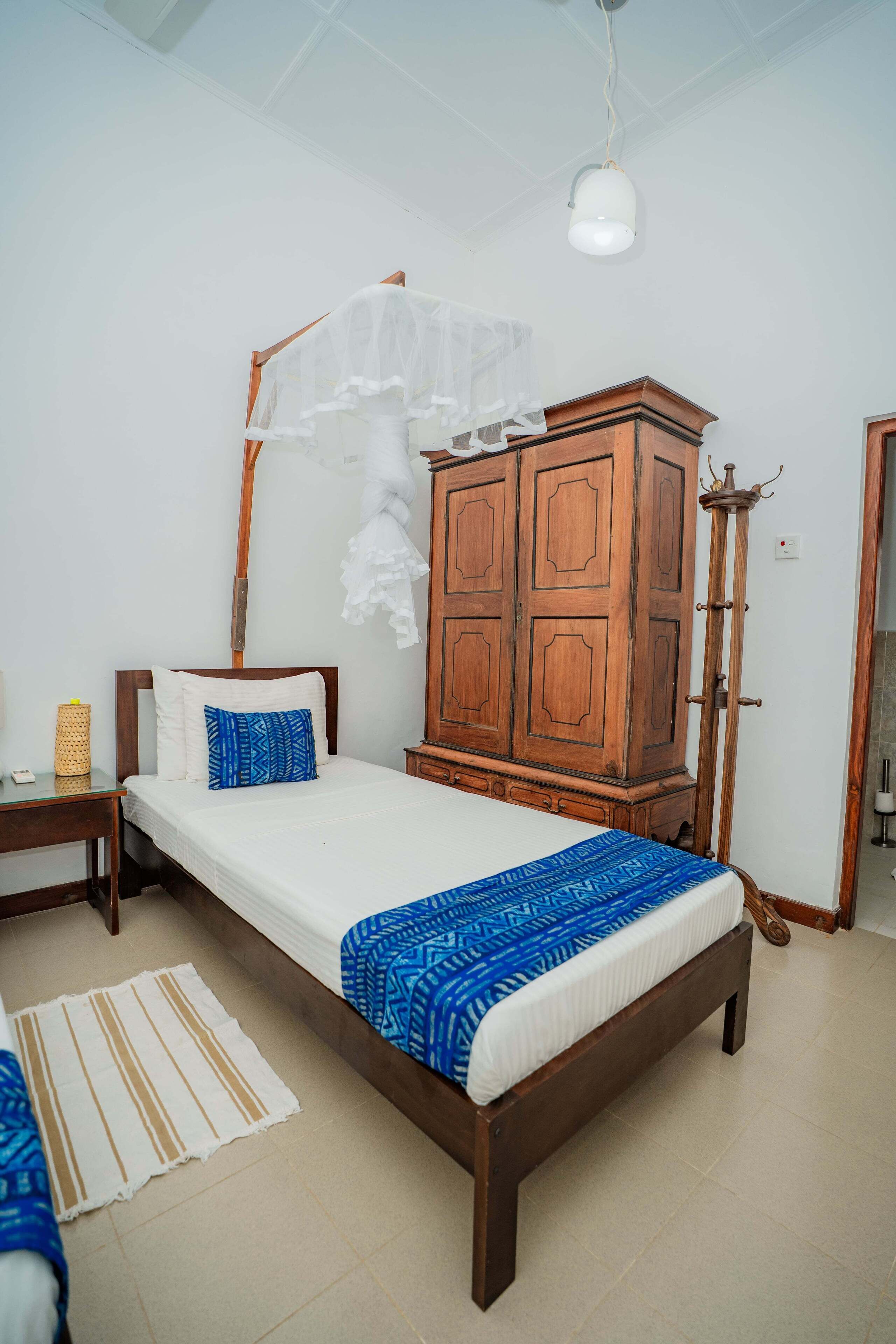 Ein Schlafzimmer mit einem Bett, einem Kleiderschrank, einem Nachttisch und einer Stehlampe.