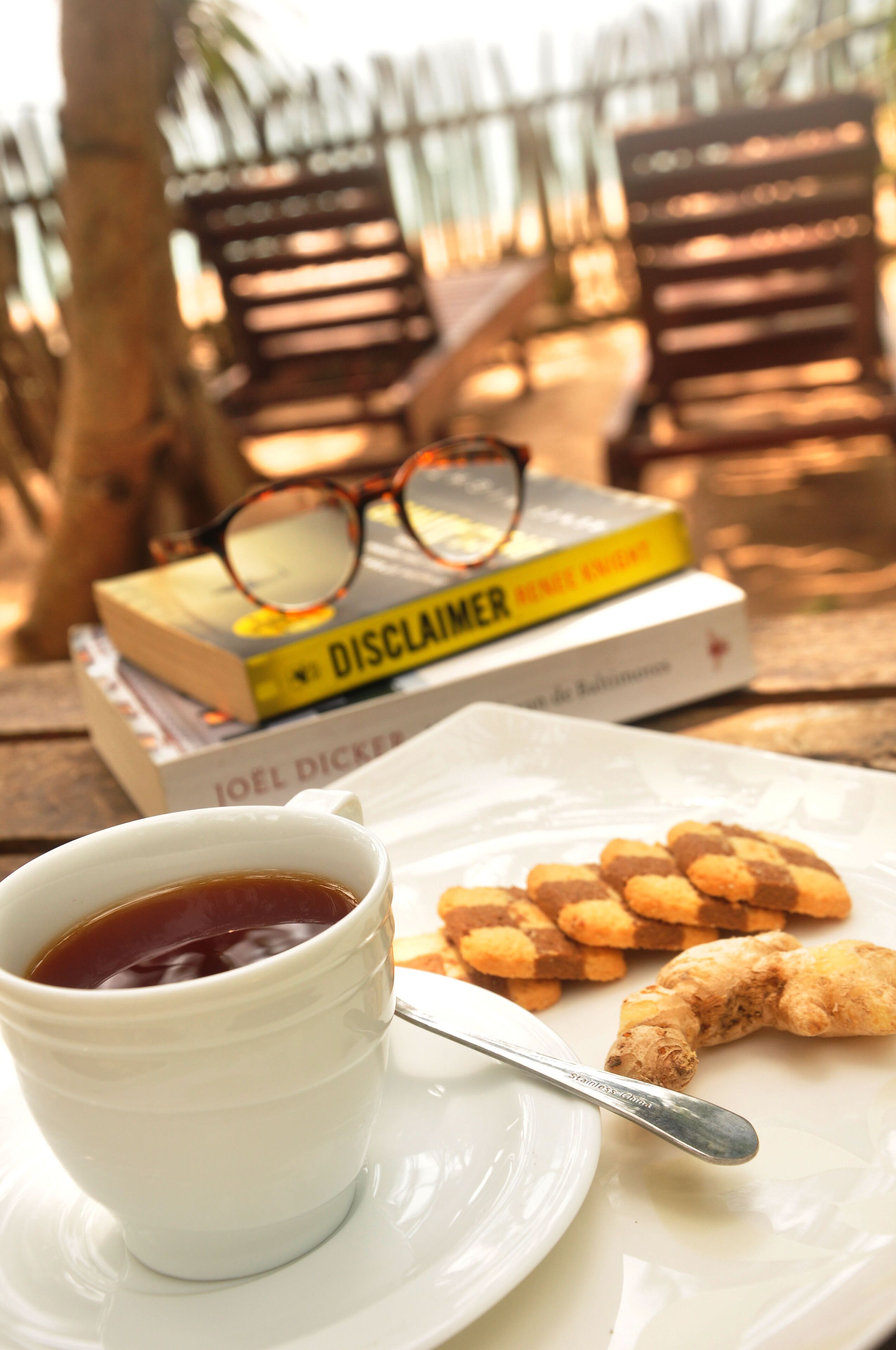 Una mesa con una taza de té, un plato de galletas y una pila de libros.