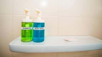 Two bottles of shampoo and body wash on a bathroom shelf.