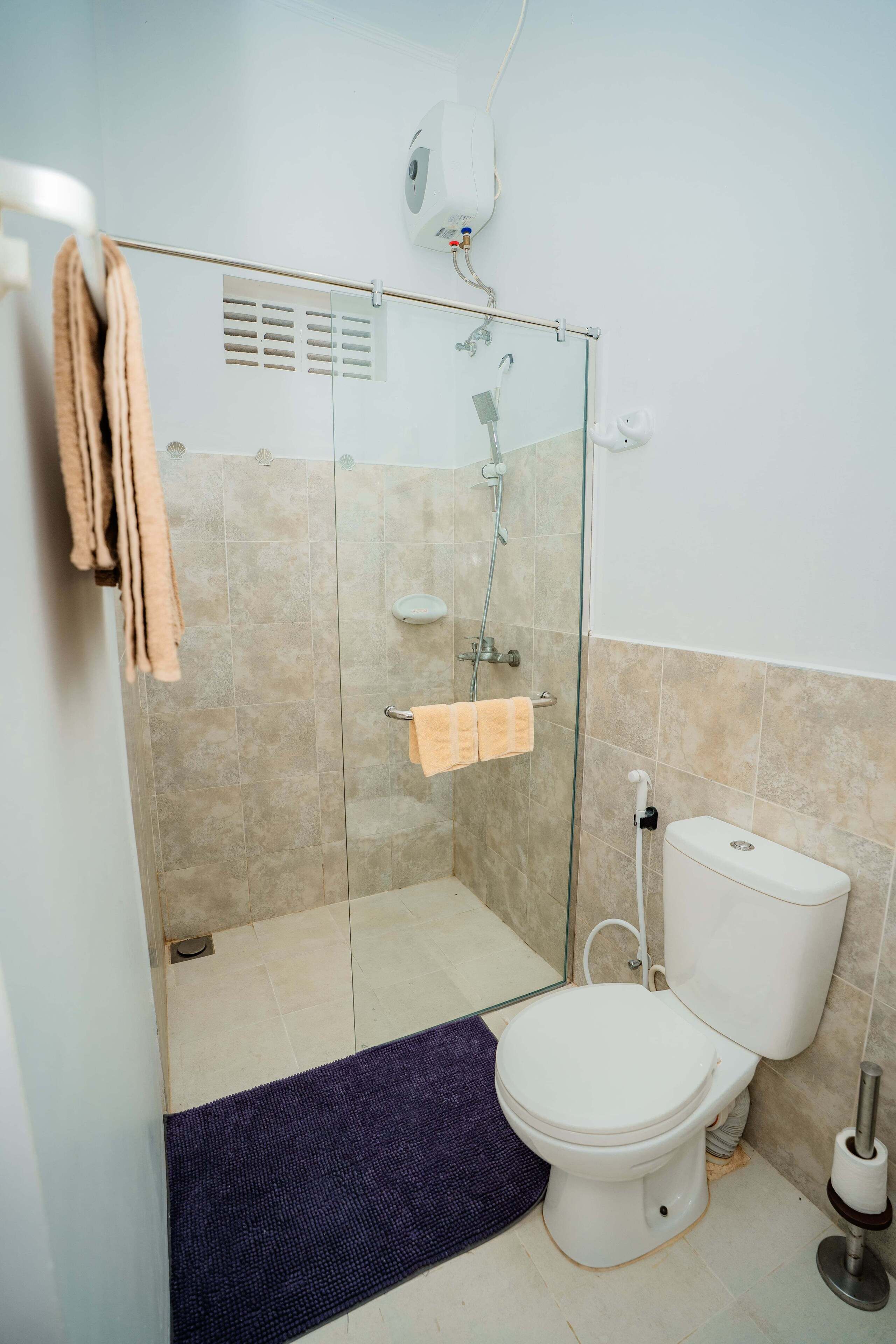 A bathroom with a glass-enclosed shower, a toilet, and a towel rack.