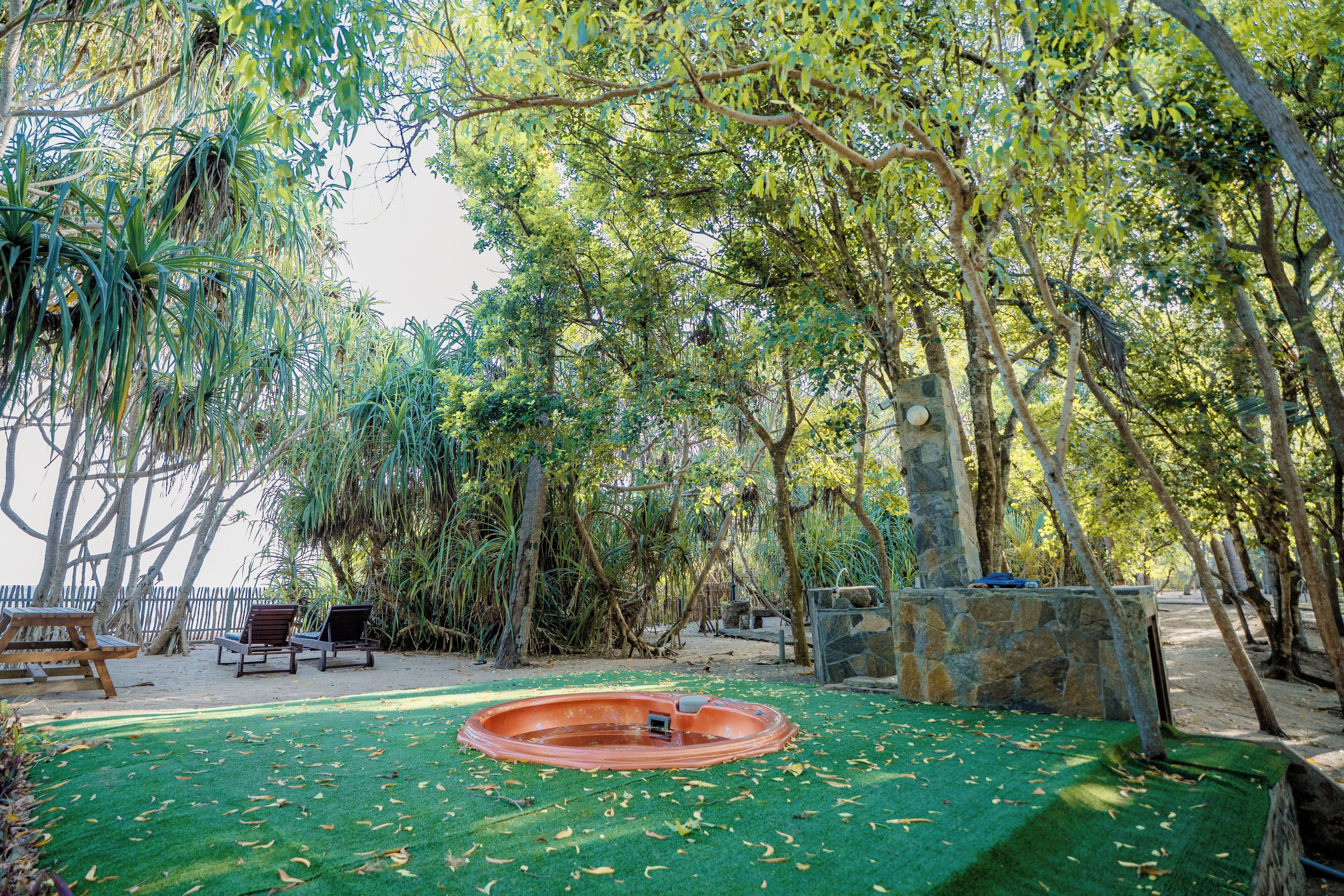 Un jardín con piscina, sillas de descanso y un muro de piedra.