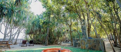 Un jardín con piscina, sillas de descanso y un muro de piedra.