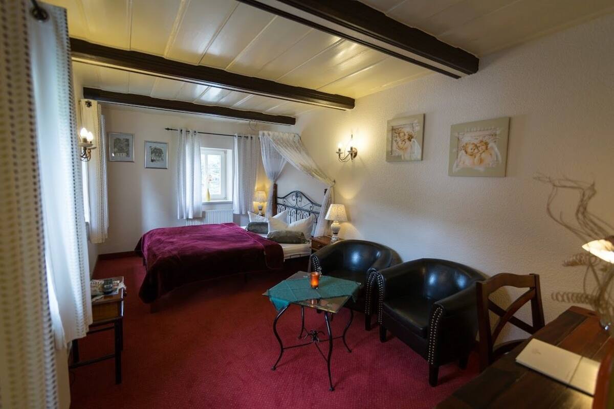 Une pièce confortable avec un lit, une chaise, une table et une lampe.