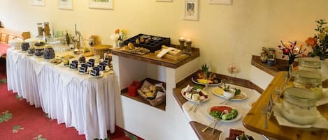 A buffet setup with various food items and beverages, a red carpet, and framed pictures on the wall.