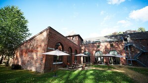 A brick building with arched windows and a staircase. - Hotel Le Val Fayt (Manage)
