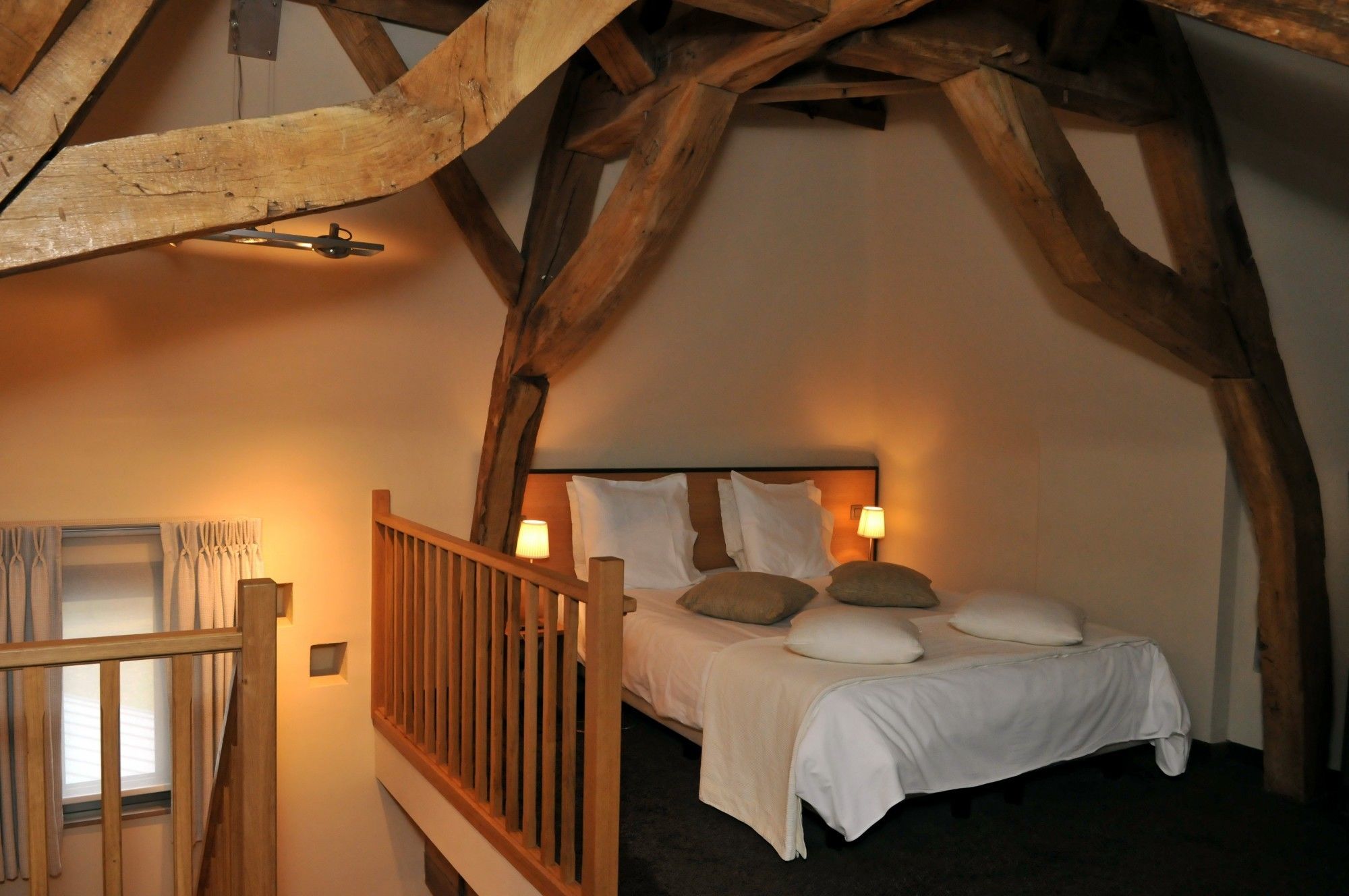 Een gezellige slaapkamer met een houten plafond, een bed met witte beddengoed en twee bedlampen.