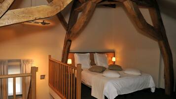 Een gezellige slaapkamer met een houten plafond, een bed met witte beddengoed en twee bedlampen.