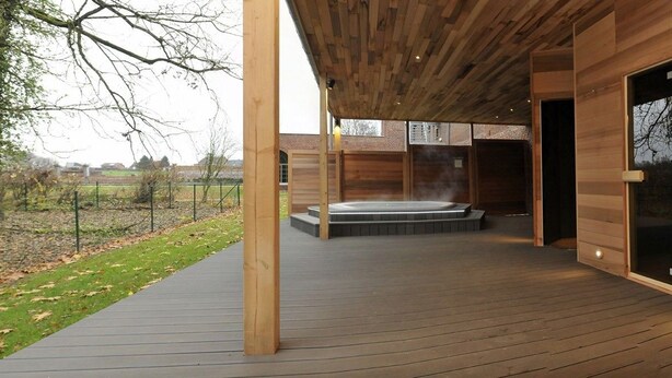 A wooden spa building with a hot tub, wooden deck, and sliding glass doors. - Hotel Le Val Fayt (Manage)