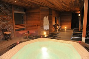 Spa-område med jacuzzi, trævægge, murstensvæg og siddeplads med håndklæder.